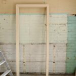 Renovation scene featuring ladder, frame, and tools against partially demolished walls.