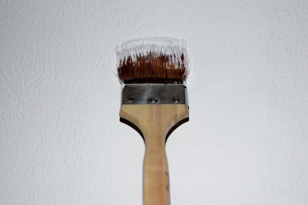 Maler beim Streichen von Wand und Decke mit Pinsel
