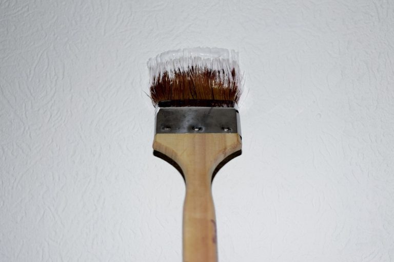Maler beim Streichen von Wand und Decke mit Pinsel